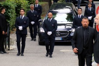 Un corbillard transporte le cercueil du défunt créateur de mode italien Giorgio Armani lors des funérailles privées lundi à l'église San Martino dans le petit village de Rivalta, près de Plaisance, en Italie. KEYSTONE/EPA/RAFFAELE RASTELLI